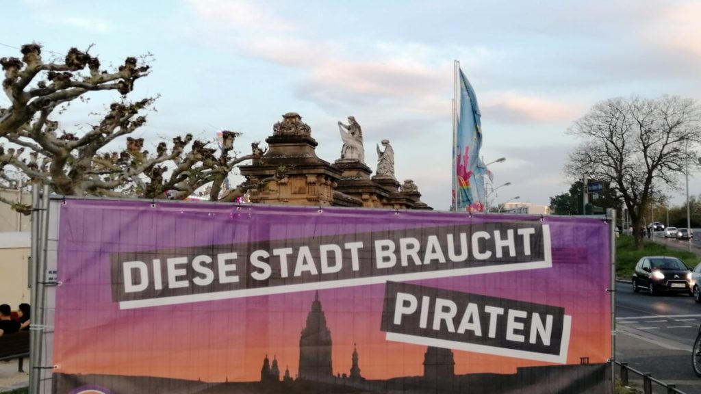 Auf dem Bild ist ein Transparent mit der Aufschrift "Diese Stadt braucht Piraten" zu sehen.