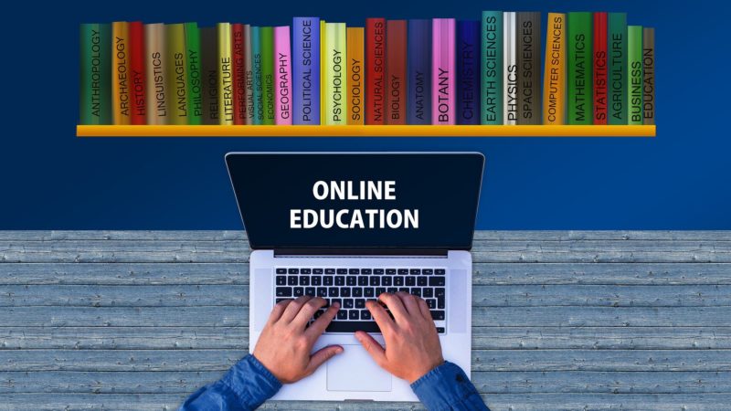 Notbook mit den Worten Online Education vor einem Bücherregal